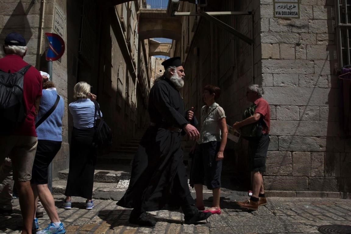 Все по той же улочке рядом с туристами идет православный священник.