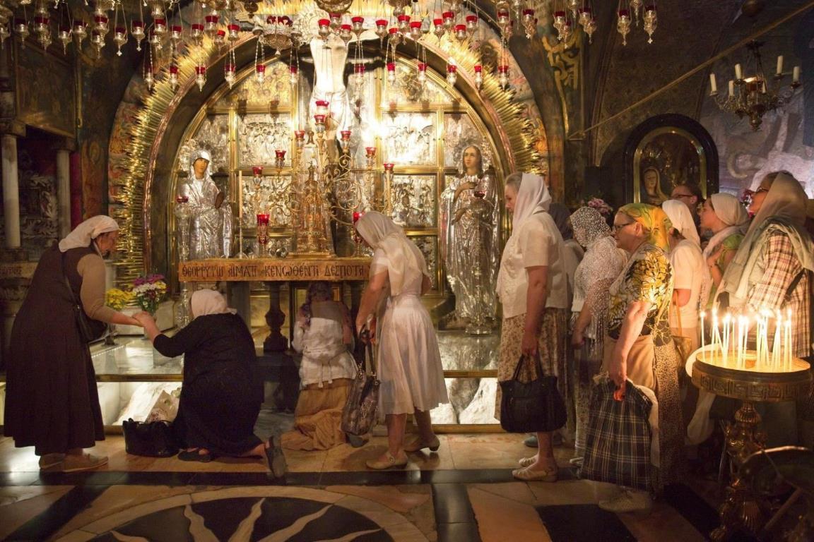 Православные паломники по очереди встают на колени, чтобы поцеловать то место, где был распят Иисус на 12-ой остановке Крестного пути.