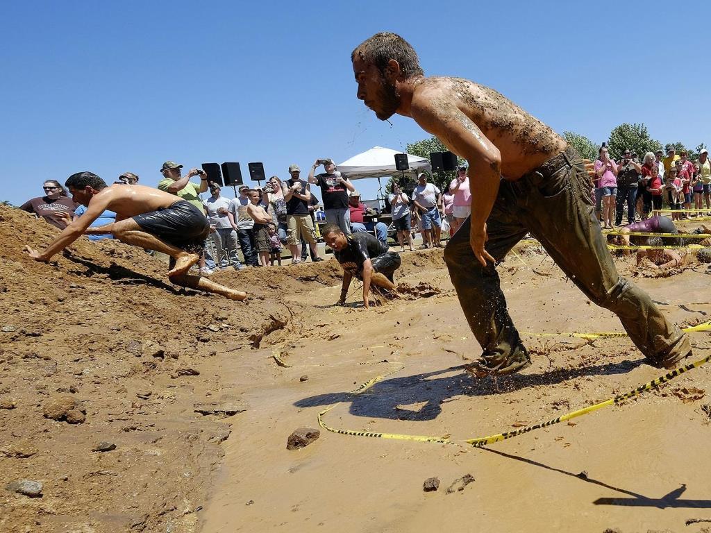 Во время одного из конкурсов бегуны выбираются из грязевой ямы.