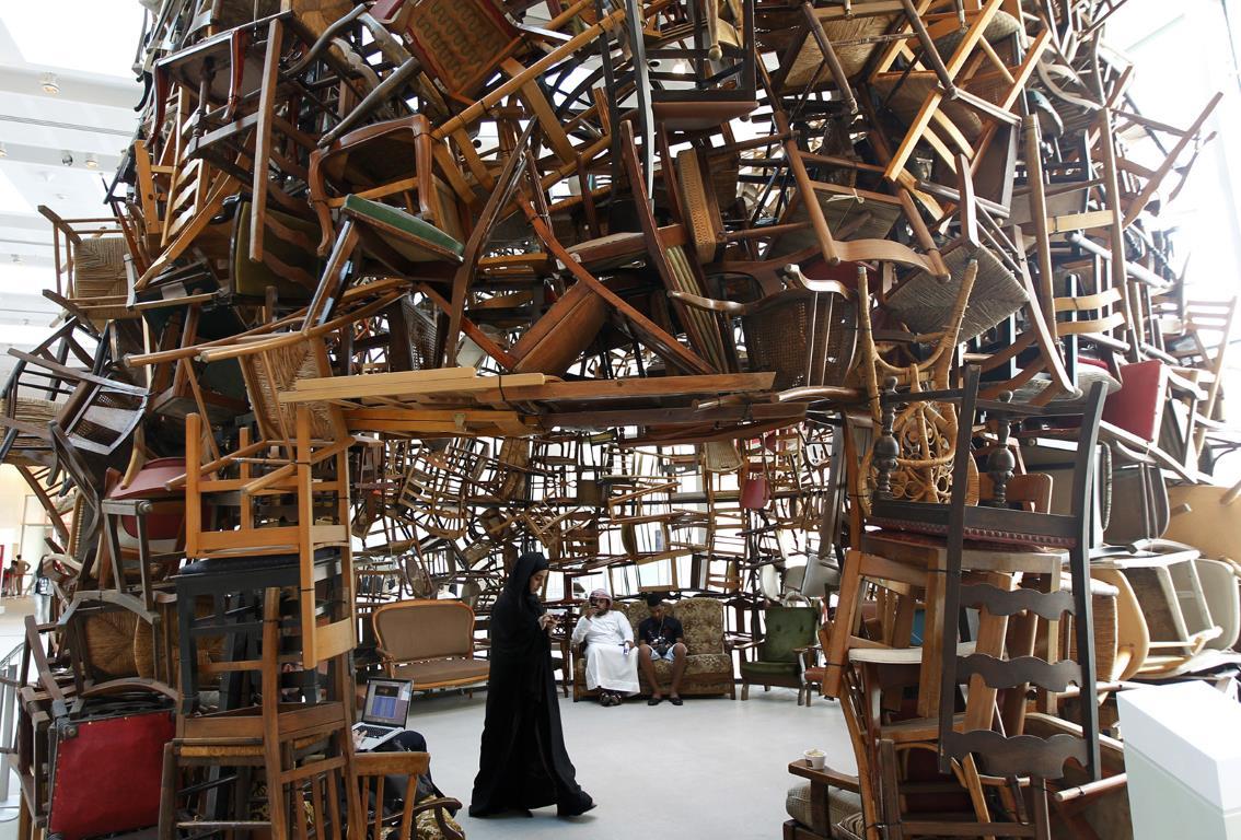 Посетитель проходит под скульптурой известной как "Стулья" (Chairs), сделанной из деревянных стульев японским художником Тадаши Кавамата (Tadashi Kawamata), во время "Abu Dhabi Art" на острове Саадият у побережья Абу-Даби.